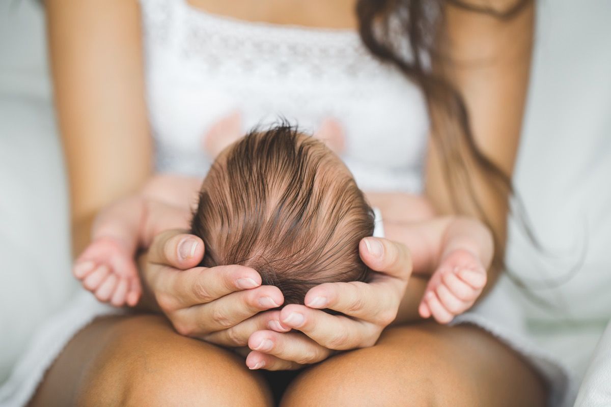 Žena drži novorođenče u krilu, tinejdžerska trudnoća