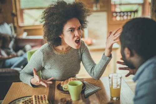   млада чернокожа жена крещи на черен мъж, докато закусва
