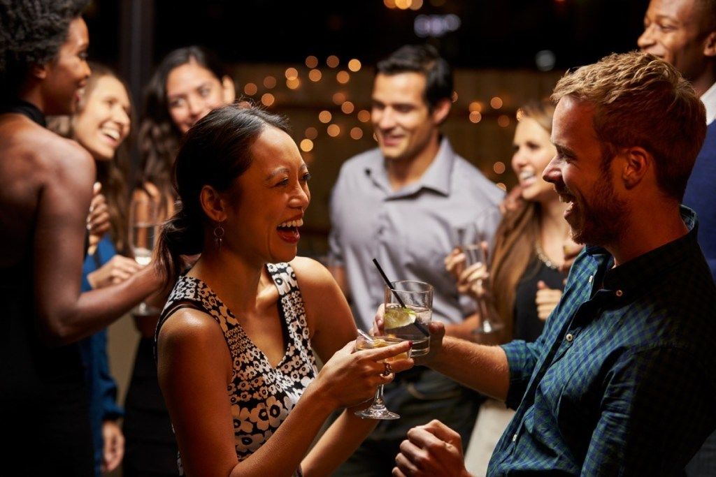moteris ir vyras juokdamiesi kokteilių vakarėlyje, pirmojo pasimatymo idėjos