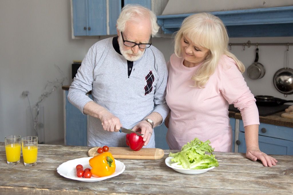 pareja de ancianos cocinando una comida saludable, nido vacío