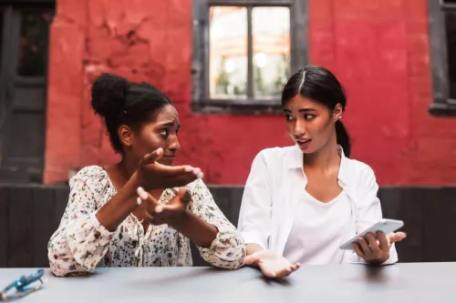   نوجوان سیاہ فام اور ایشیائی خواتین سرخ عمارت کے سامنے باہر بحث کر رہی ہیں۔