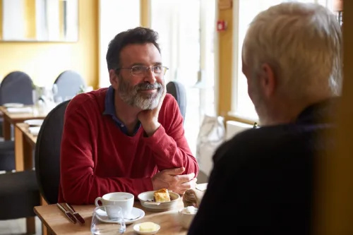   bărbat alb gay mai în vârstă care bea cafea în fața celuilalt bărbat