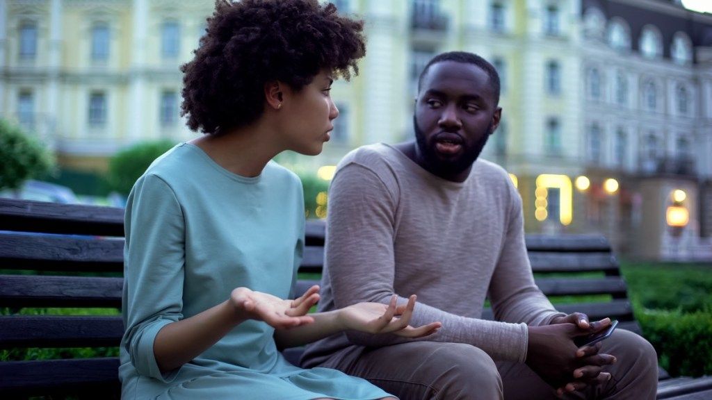 joven pareja negra hablando afuera en un banco