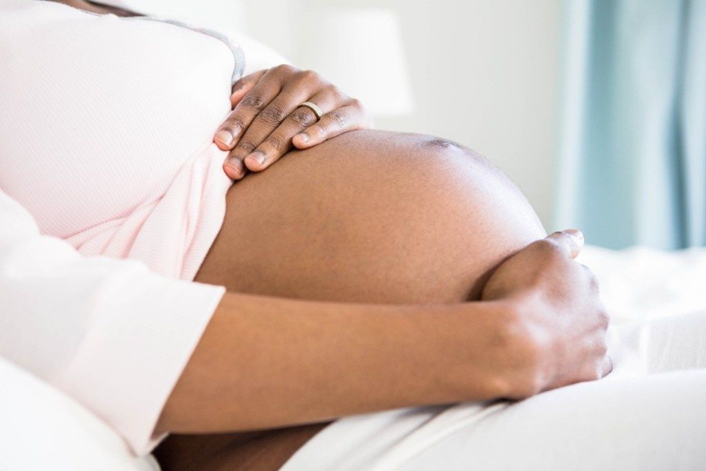 Una mujer negra embarazada tocándose el vientre de su bebé, cosas que nunca debe decirle a su cónyuge