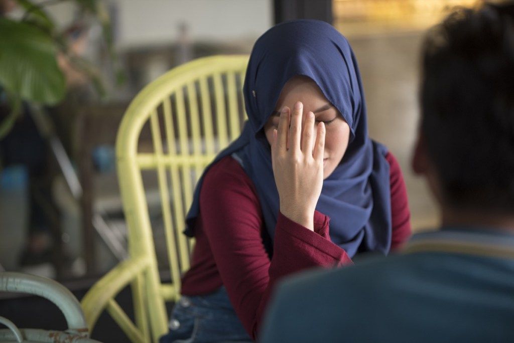 Wanita muda Muslim kesal, memegang kepala di tangan