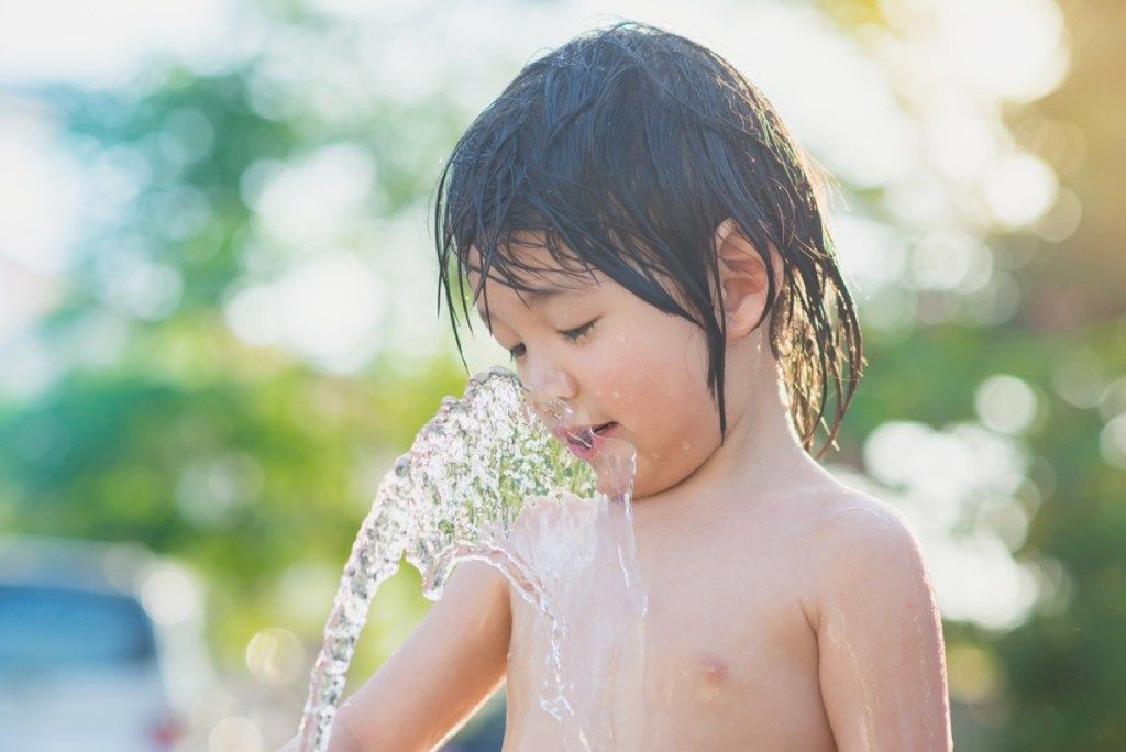 νεαρό αγόρι που πίνει νερό από μάνικα κήπου, κακές συμβουλές για γονείς