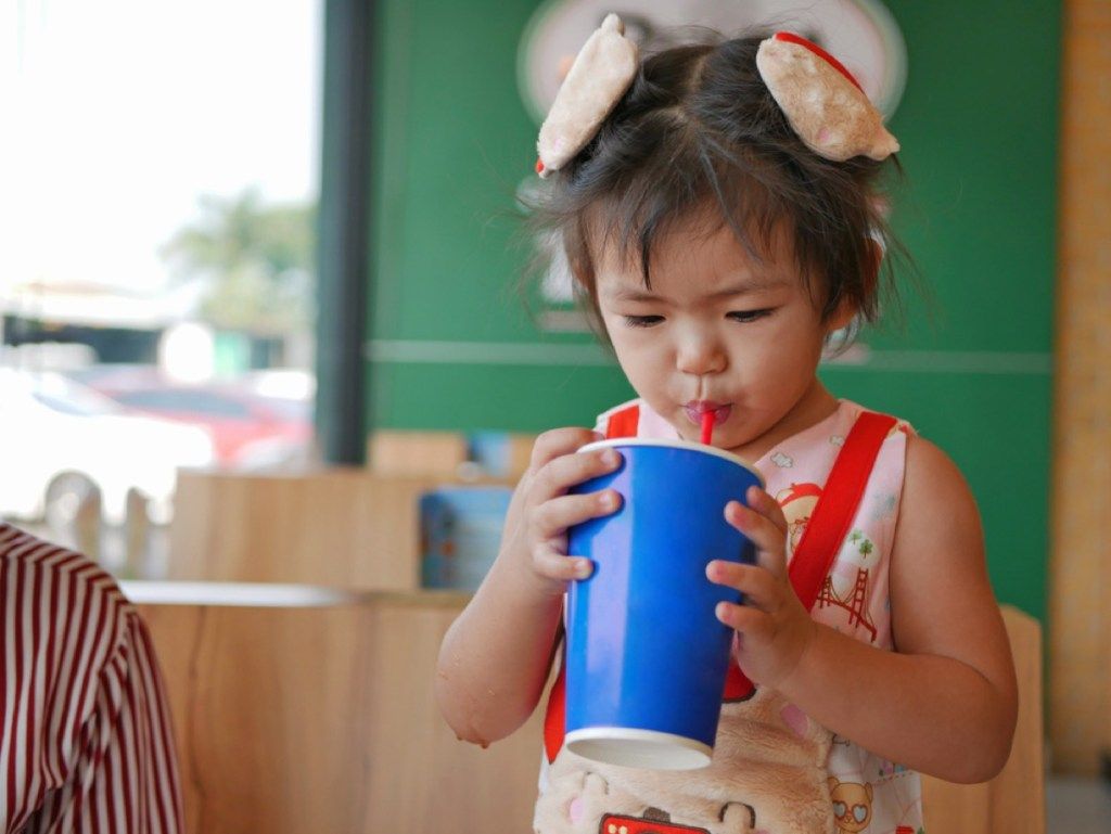 liten jente som drikker brus fra koppen med halm, dårlig foreldreråd