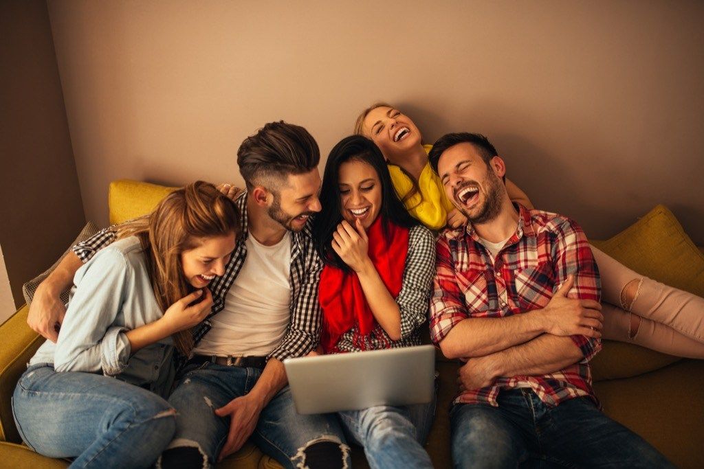 draugų grupė, besijuokianti kartu su nešiojamuoju kompiuteriu, rodo, kad jūsų vyras apgaudinėja