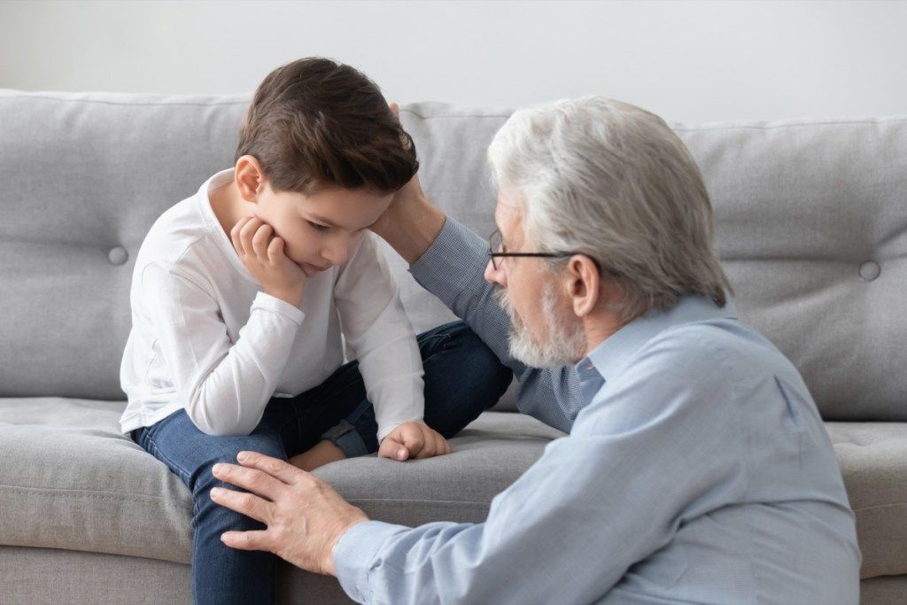 Abuelo y nieto blancos molestos en el sofá