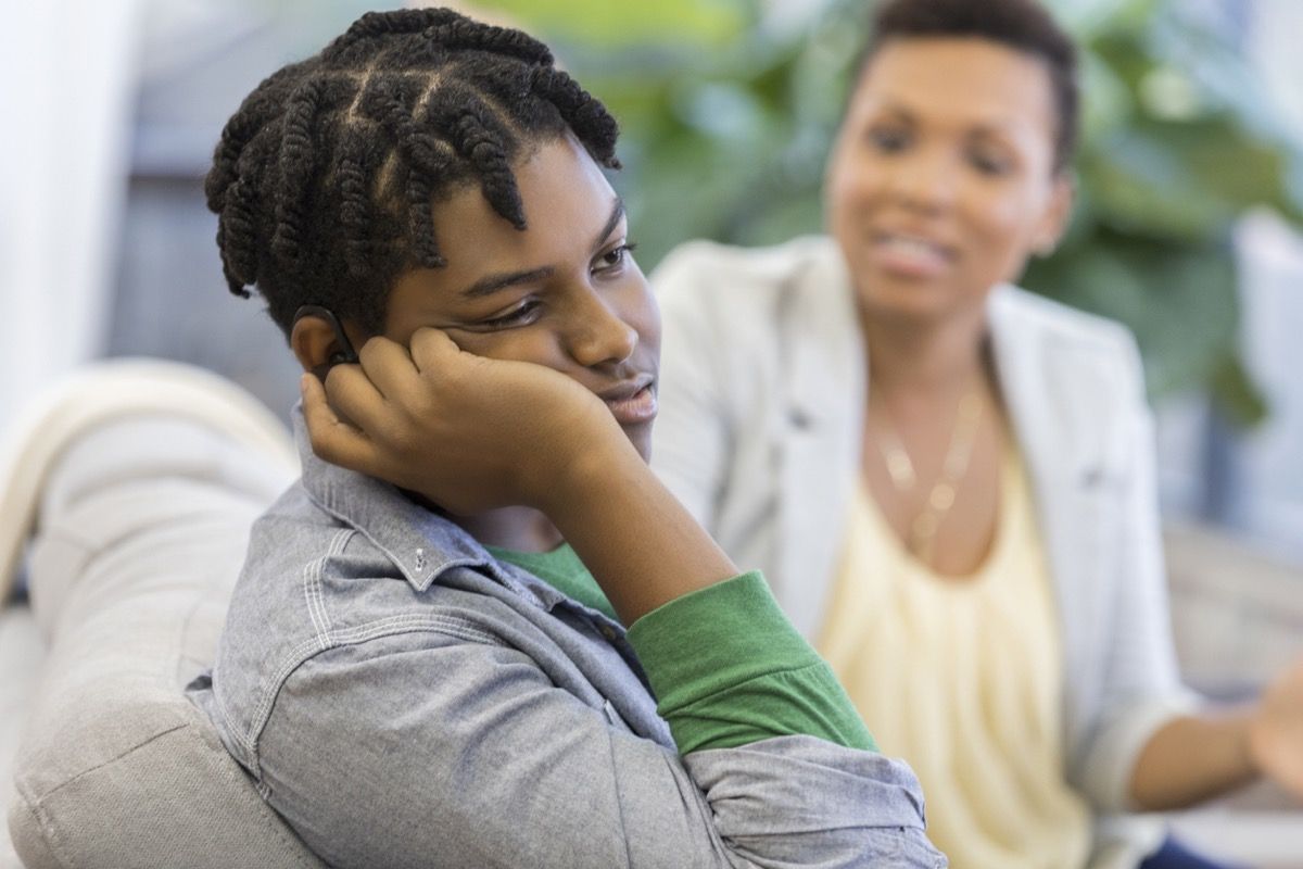 chico adolescente negro ignorando a su madre en el sofá