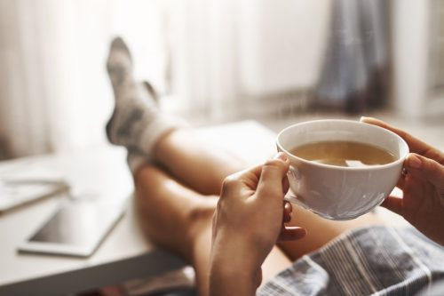   אישה שותה תה עם רגליים למעלה