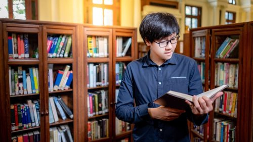   asiatisk man läser ordboken i ett bibliotek