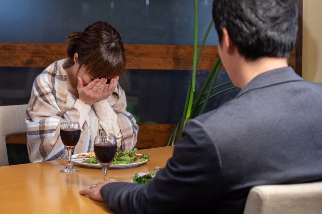 молодая азиатская женщина плачет за ужином