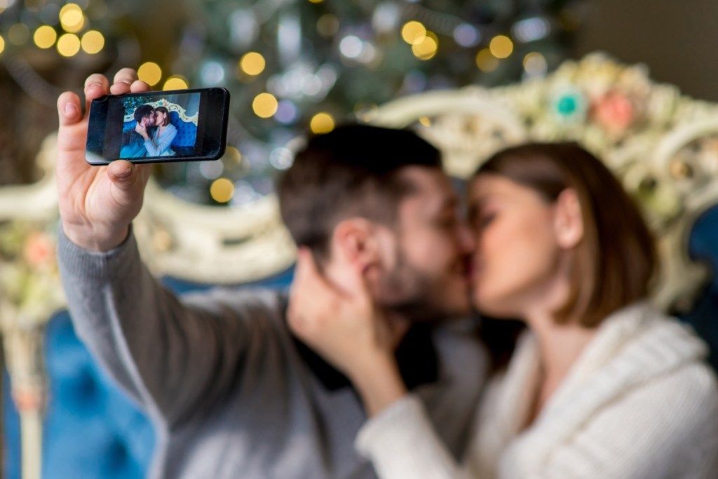30-vuotias valkoinen pariskunta suutelee ja ottaa selfietä