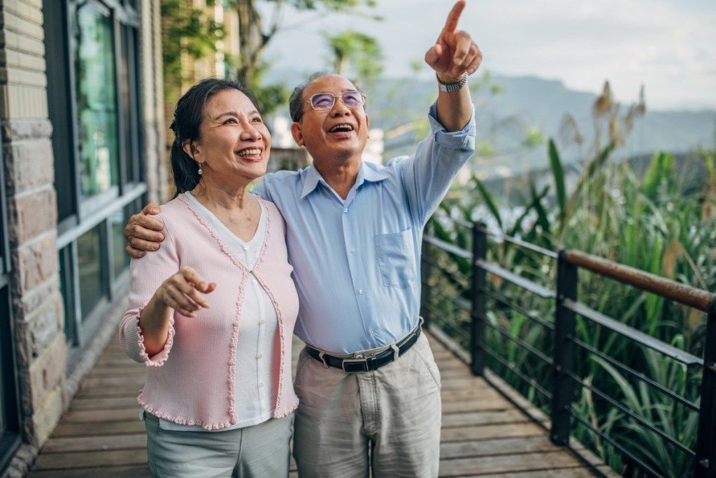 vīrietis un sieviete, vecākais precēts pāris stāv uz terases mājās kopā.