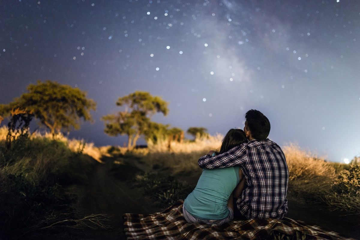 двойка се прегръща на одеяло за пикник под звездите
