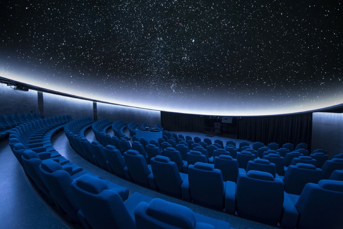 interieur van planetarium toont lege stoelen met sterrenprojectie