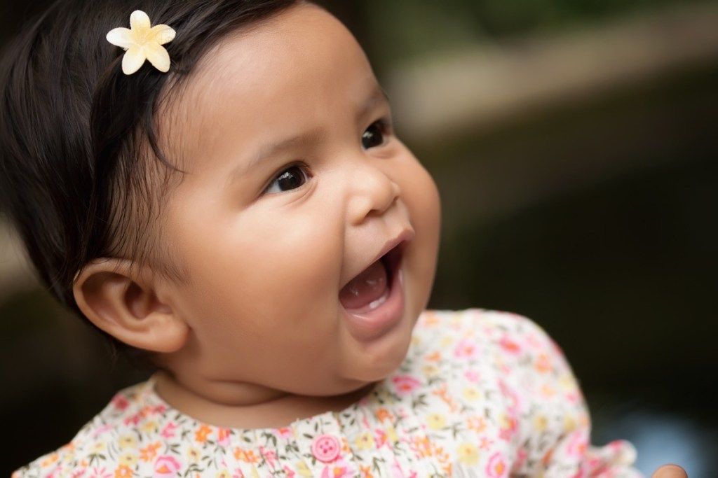 hymyilevä latinalaisamerikkalainen vauva kukka hiuksissaan