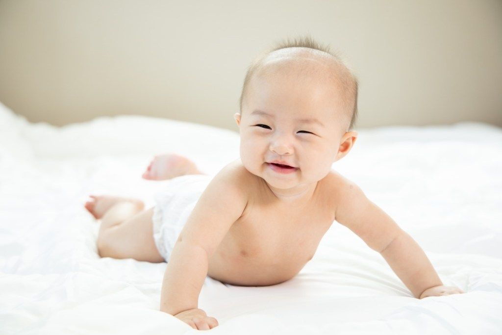 एशियाई बच्चे मुस्कुराते हुए पेट कर रही है