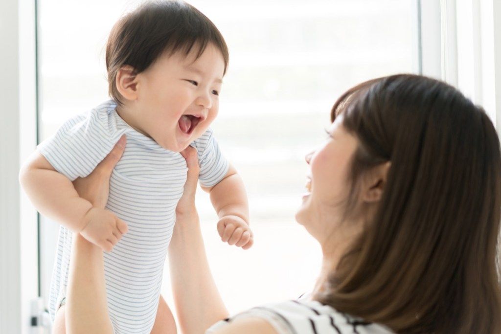 jauna azijietiška mama, laikanti kūdikį mėlyna spalva
