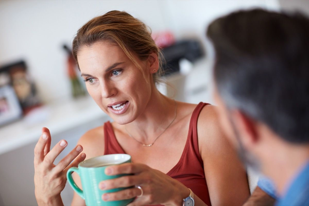 immagine ritagliata di una donna che fa domande a un uomo davanti a una tazza di caffè