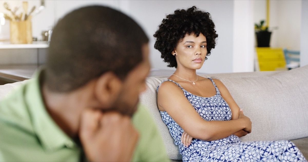 nő mérgesen bámulja partnerét, miközben a kanapén ül