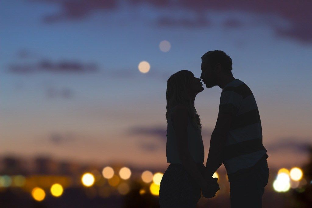 silueta páru bozkávajúcich sa na streche za súmraku