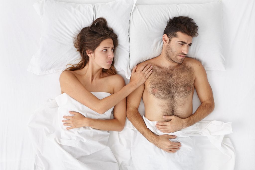 Muž bolí v posteli s partnerom