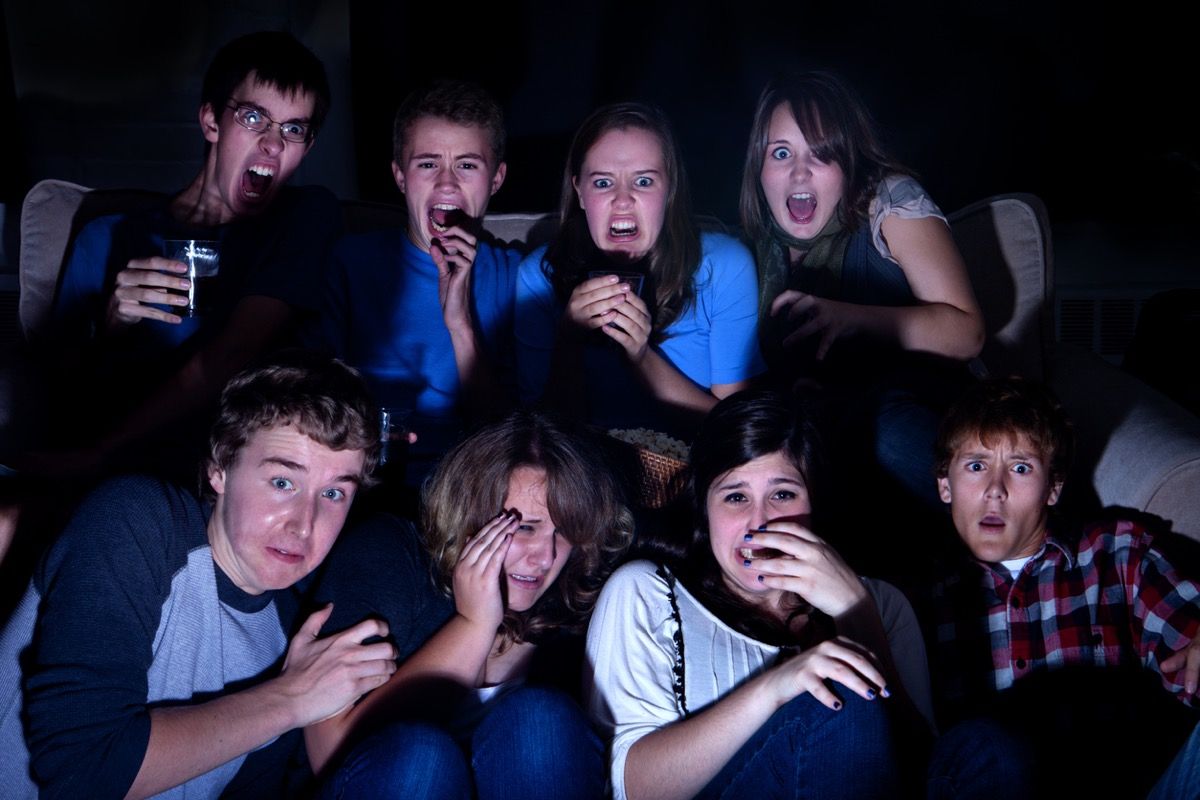เพื่อนวัยรุ่นกำลังดูสิ่งที่น่าตกใจในทีวีในความมืด