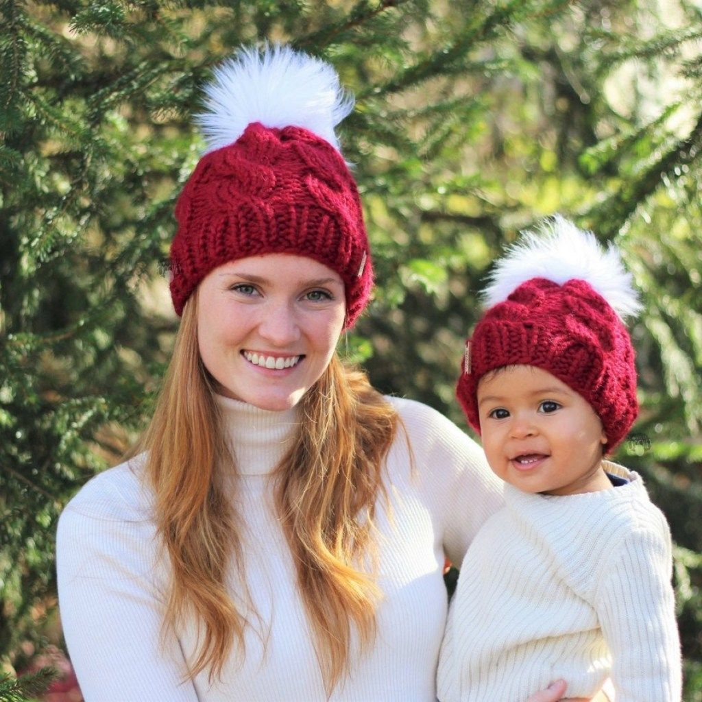 moteris ir kūdikis, derindami raudonas kepures su pom pom, motinos dukros dovanos