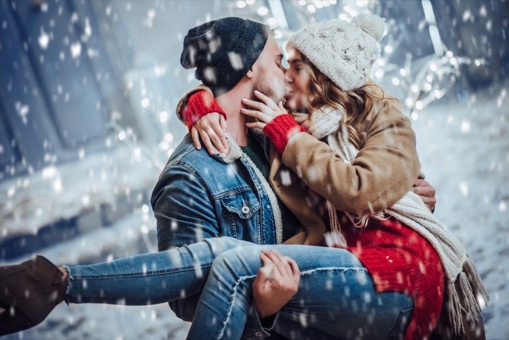 bărbat și femeie sărutându-se iarna
