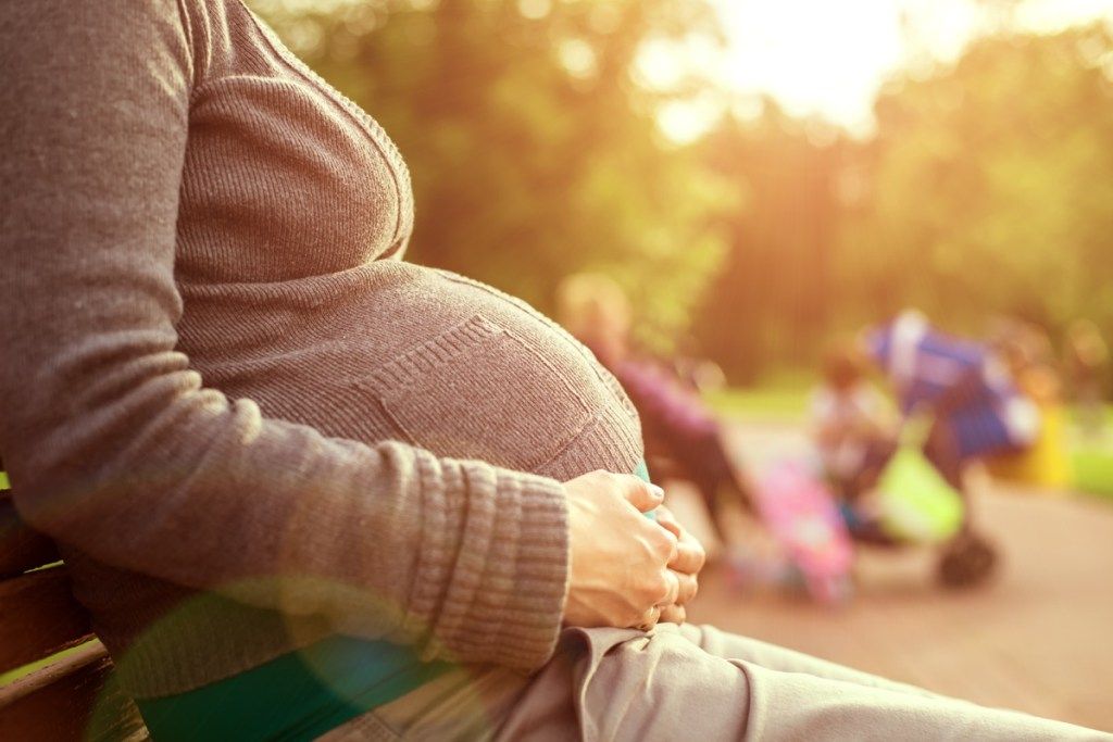 těhotná žena sedící na lavičce