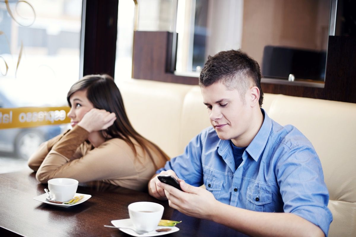 Žmogus savo telefone restorane, būdamas pasimatyme dėl socialinio etiketo klaidų