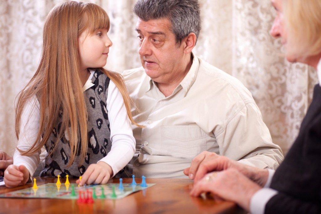 starí rodičia hrajúci s vnučkou spoločenskú hru