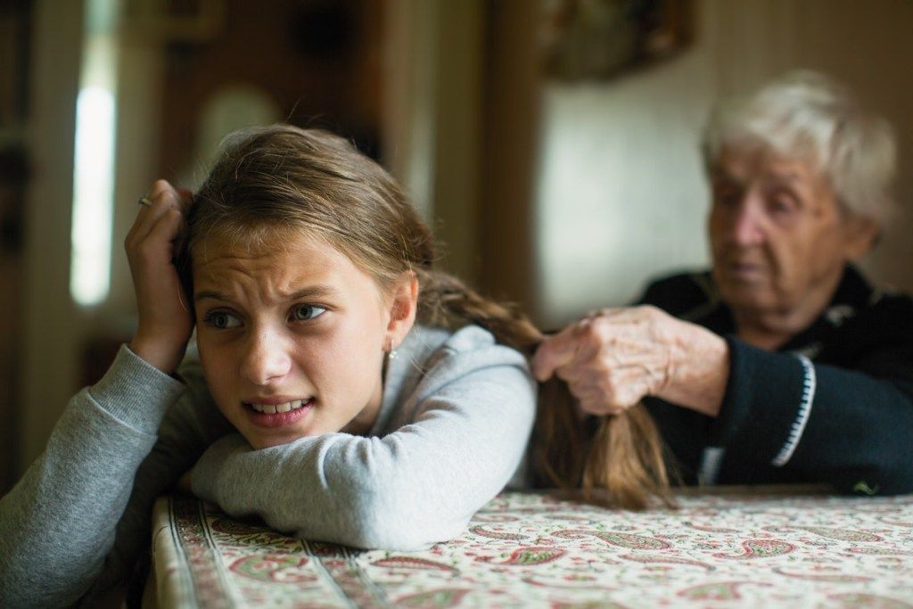 rozrušená dívka s vlasy spletené její babičkou