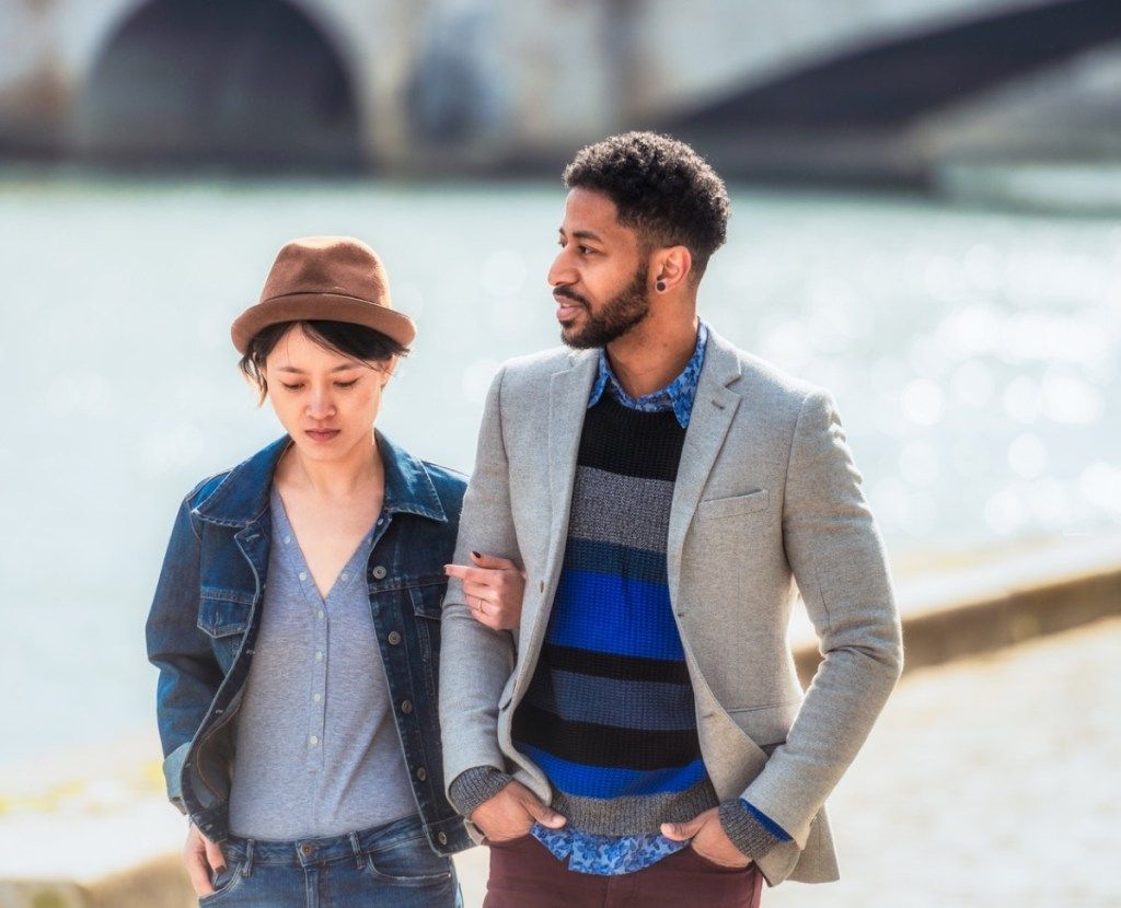 Nuori pariskunta keskustelee yhdessä kävellessään Seinen rannalla.