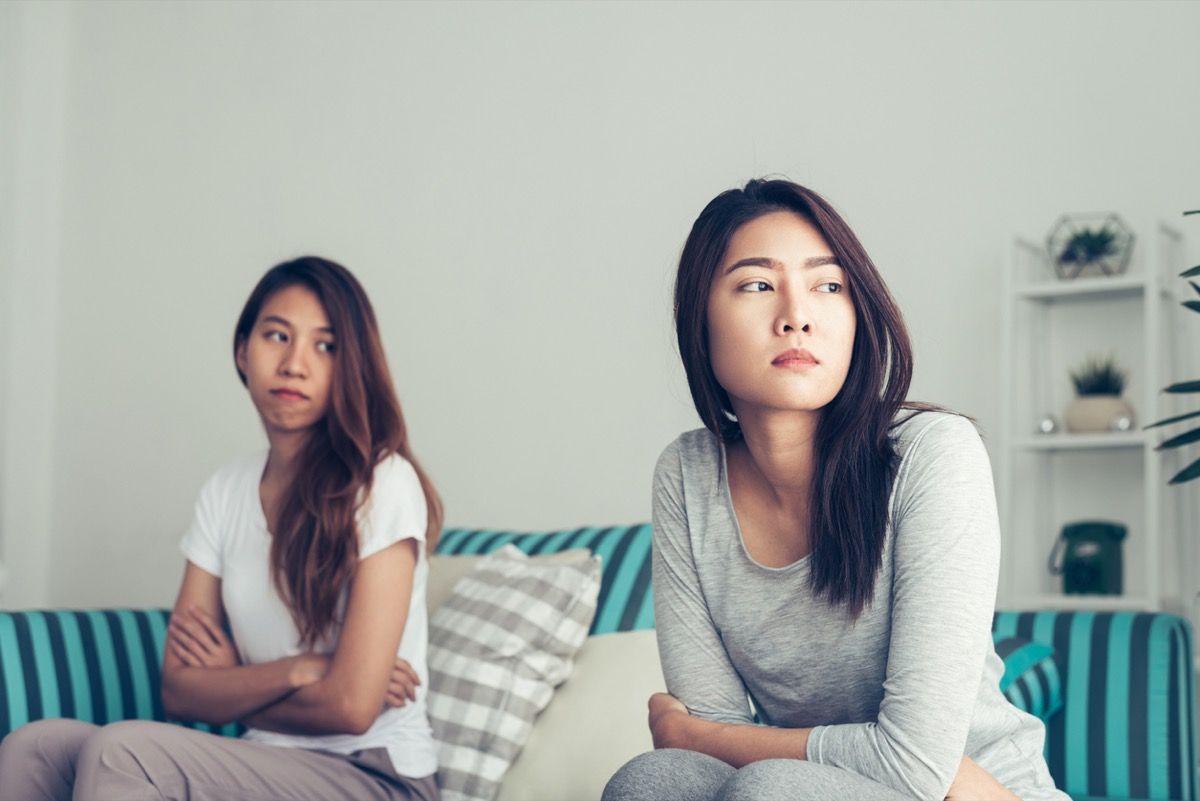 Unga asiatiska lesbiska par argumenterar och vänder ryggen mot varandra i sovrummet