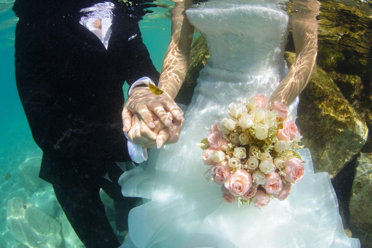 brudgom og brud holder hendene under vann, de galeste ting brudeparet noensinne har gjort på bryllup