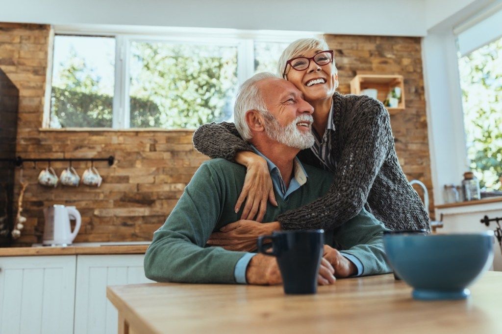 キッチンで抱きしめて笑っている年配のカップル