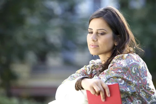   жена от Близкия изток изглежда замислена, докато държи дневник