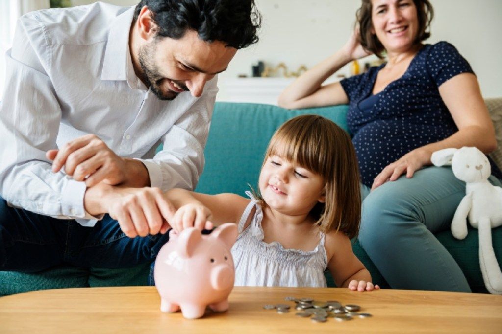 ילדה צעירה שמה מטבעות בבנק החזיר, כישורים שהורים צריכים ללמד ילדים