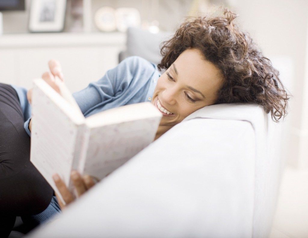 امرأة لاتينية تقرأ كتابًا على الأريكة