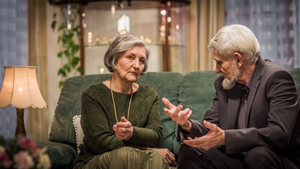 زوجان مسنان يجلسان على أريكة غرفة المعيشة ويخوضان محادثة جادة.