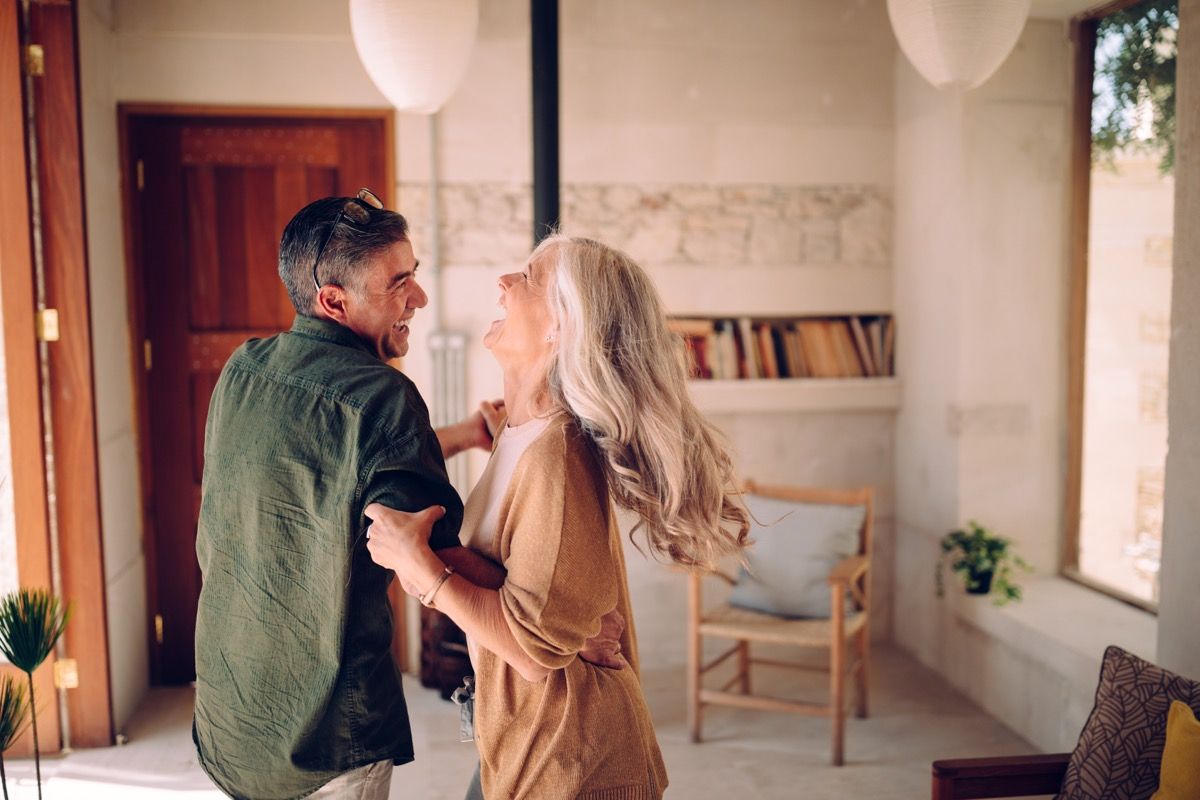 Laiminga vyresnio amžiaus pora kartu šoka ir juokiasi namuose