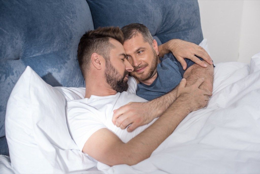 middelaldrende homofilt par som koser seg i sengen