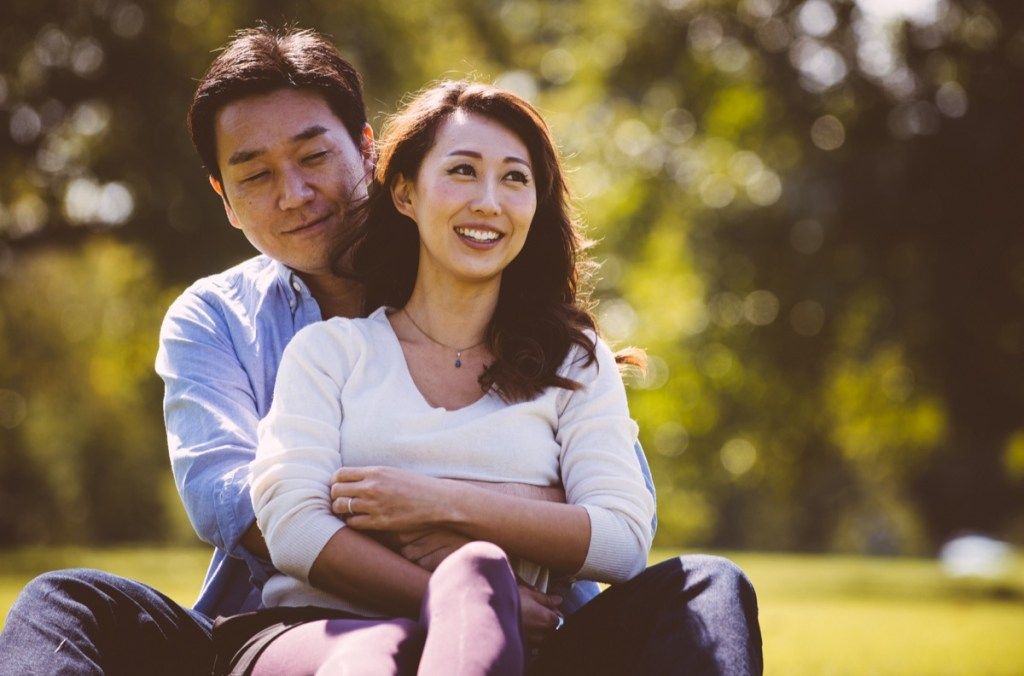 คู่รักชาวเอเชียวัยกลางคนนั่งอยู่บนพื้นหญ้า
