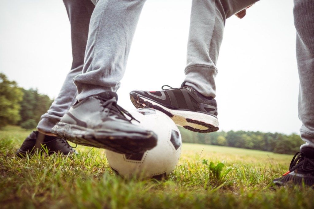 Dos hombres jugando al fútbol en pantalones de chándal gris sobre el césped
