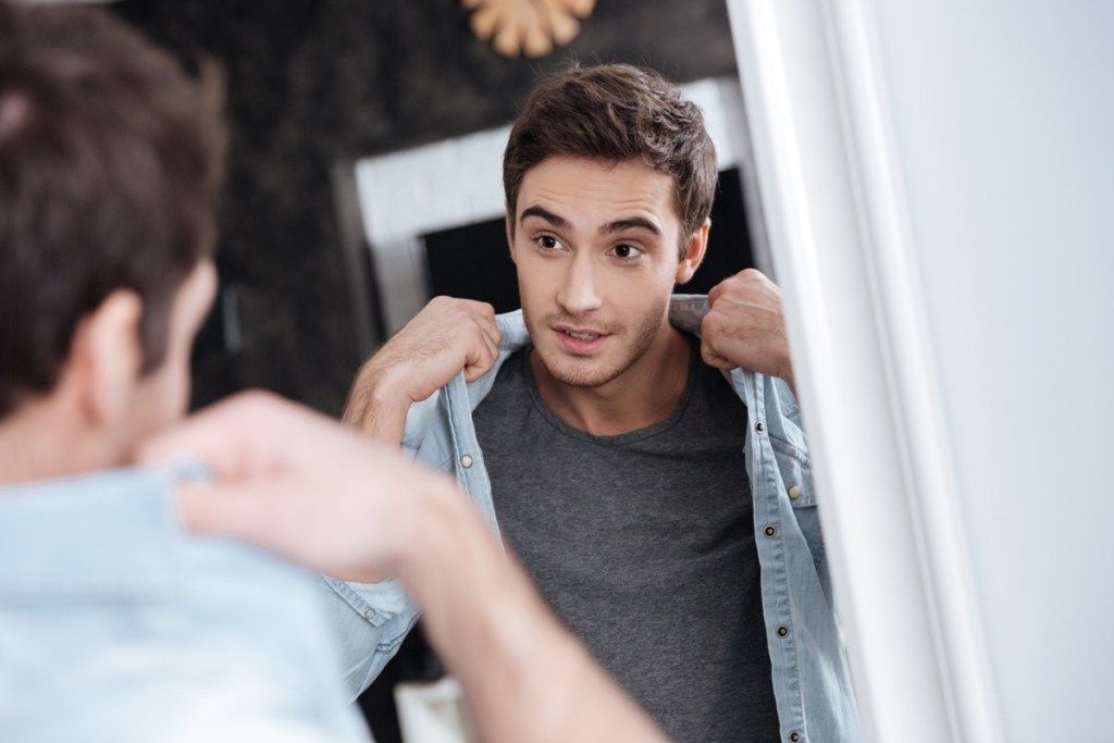 vyras žiūri į savo drabužius veidrodyje, santykių baltumo melas