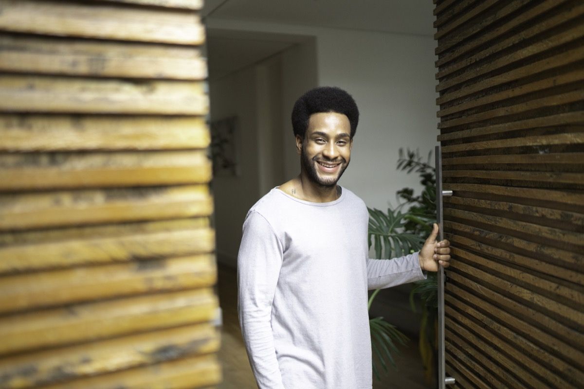 fekete ember kinyitja otthonának ajtaját és mosolyog