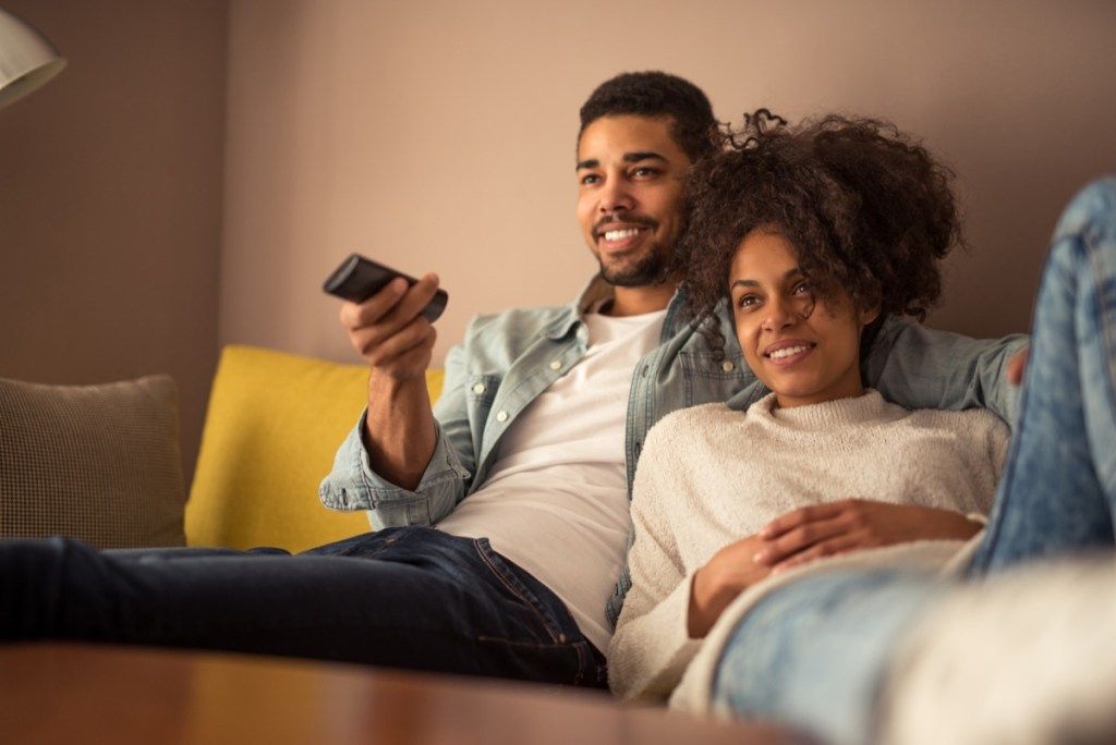 Ett ungt par som tittar på TV, förhållandevitt lögner